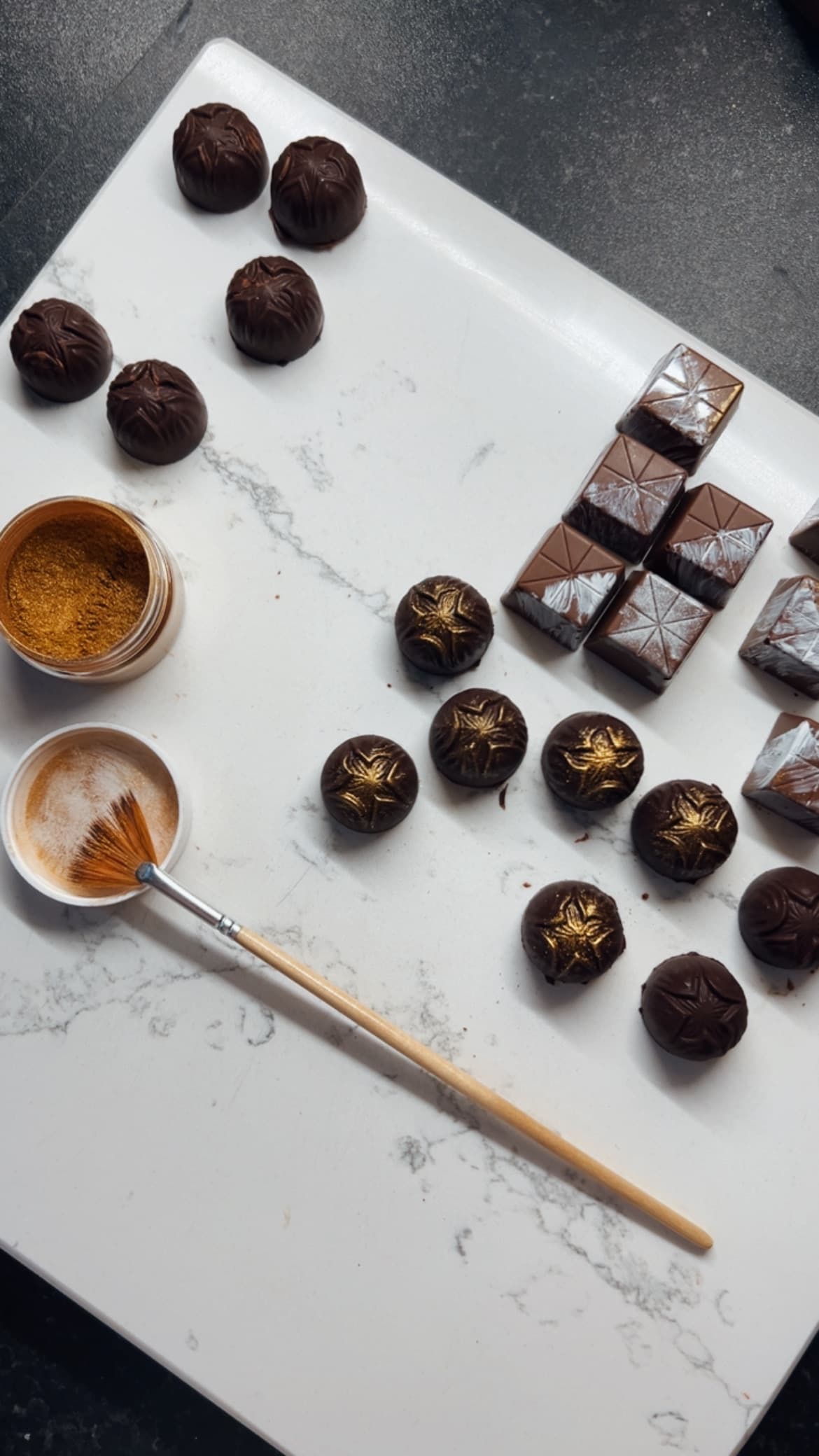 Pralines being gilded by hand with gold dust in the atelier